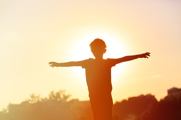 Obraz na płótnie Canvas silhouette of happy little boy at sunset