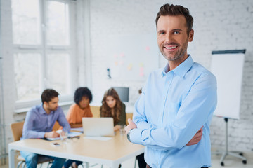 Portrait of cheerful business man standing in modern office with