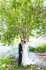 wedding couple kissing against the backdrop of  a misty garden.