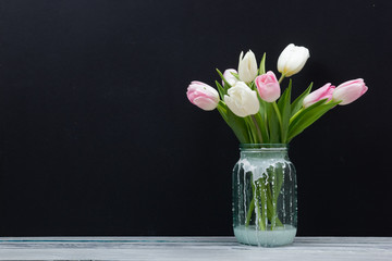 Colorful tulips flowers on black board background wooden table. Top view with copy space