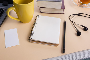 Office table desk with supplies, white blank note pad, cup, pen, pc, crumpled paper, flower on wooden background. Top view