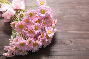 Pink flowers are on the wooden background with ribbon