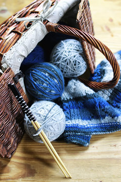 balls of wool and knitting needles on background