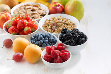fresh berries, fruit and muesli for breakfast on white table