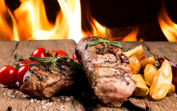Grilled steaks on wooden table 