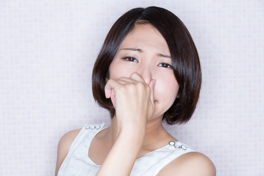鼻をつまむ女性