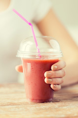 close up of woman holding cup with smoothie