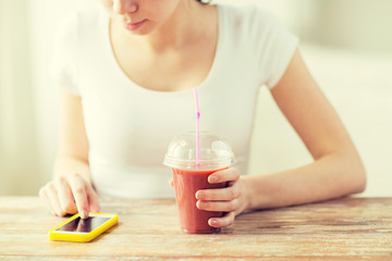 close up of woman with smartphone and smoothie