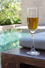 Glass of wine on the bed beside the pool
