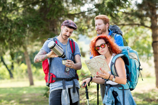 Sports people with backpack in forest with hiking sticks