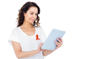 Naklejka premium Woman with red aids awareness ribbon using tablet