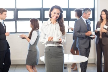 Businesswoman smiling at camera while her colleagues standing
