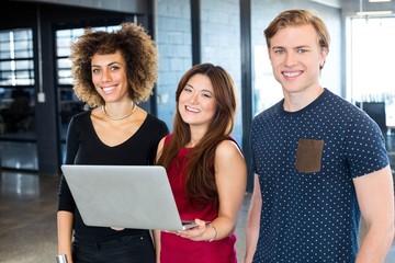 Portrait of colleagues holding laptop and smiling