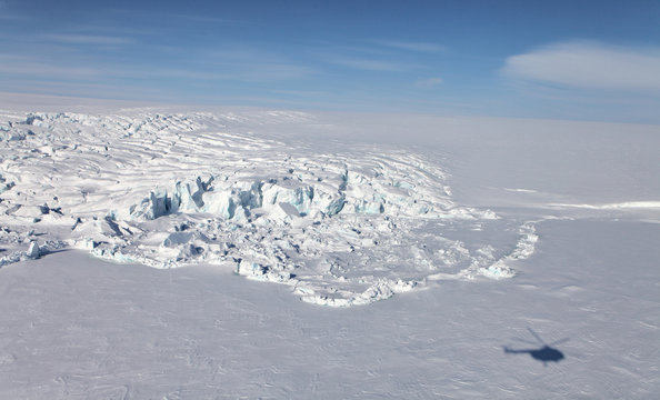 Aerial view of iceberg in frozen Arctic Ocean and helicopter shadow