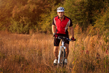 Obraz premium Man is riding a mountain bike in the field