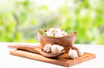 Obraz na płótnie Canvas Fresh mushrooms champignons in bowl. Nature green background