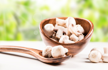 Fresh mushrooms champignons in bowl. Nature green background