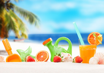 orange juice and summer accessories on sand with tropical beach background