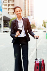 Business woman pulling suitcase walking in city