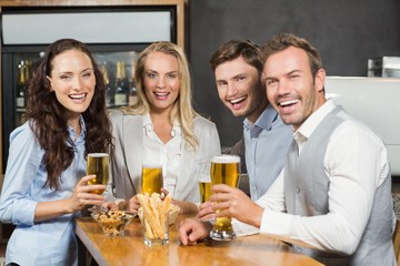 Friends smiling at camera with beers in hand