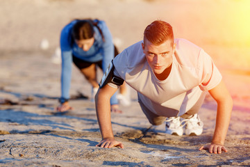 Young couple doing push ups on ocean beach