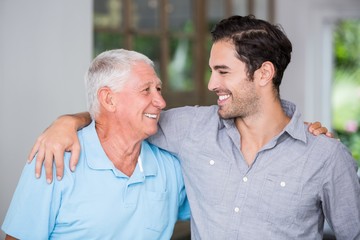 Smiling father and son with arm around - obrazy, fototapety, plakaty