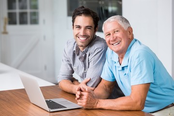Portrait of smiling father and son with laptop