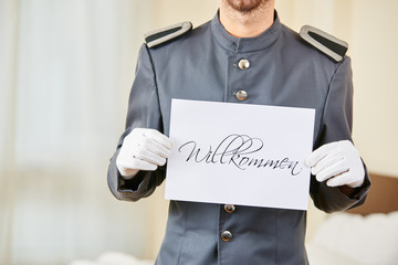 Diener im Hotel hält Willkommen Schild