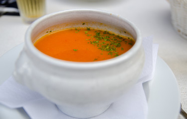 Pumpkin soup and parsley leaf in a white bowl