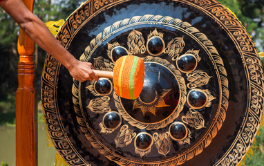 Hand hit big gong in temple