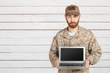 Portrait of young army soldier with a laptop