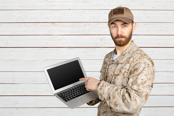 Portrait of young army soldier with a laptop