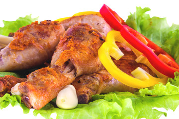 Three roasted chicken legs with salad leaves with bell pepper and garlic.