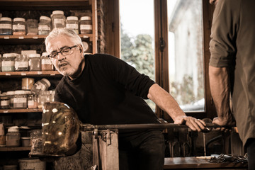 Glassblower forming molten glass in his worshop