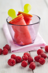 Hand made raspberry ice pops in a glass with fresh raspberries