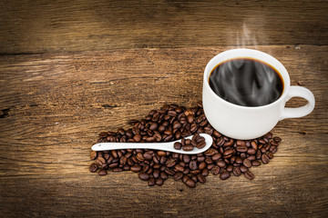 Coffee beans and cup on old wooden background