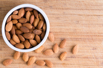 Bowl of fresh raw almonds on an old wooden board