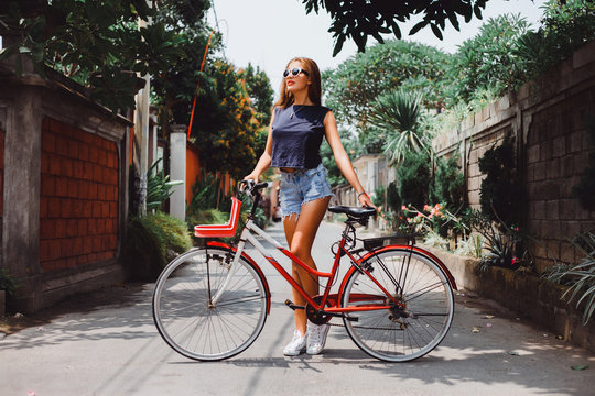 Young sexy woman,wear denim summer outfit and holding mirrored sunglasses,perfect glowing tan skin,attractive and,joy and happiness,trim,athletic figure,perfect female body, and drift show