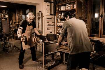 Glassblower forming molten glass in his worshop