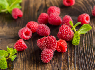 Fresh ripe raspberries and mint's leafs on old wooden table