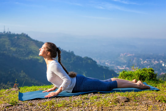 Woman practices yoga asana bhujangasana cobra pose