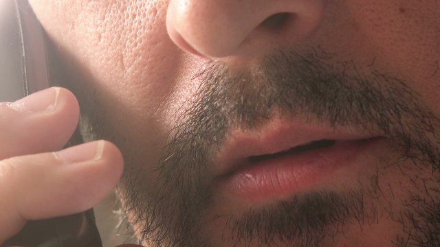 Unshaven Adult Caucasian Male Having Private Conversation Over Land Line Telephone, Close Up Detail Of Face, Beard And Mouth Talking.