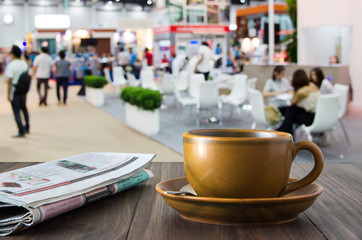 brown coffee cup and newspaper on blurred event background