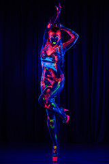 Female pole dancer in bright neon colours under ultraviolet (UV) light on background