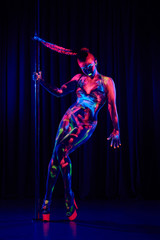 Fototapeta na wymiar Female pole dancer in bright neon colours under ultraviolet (UV) light on background