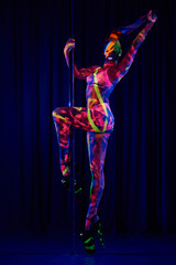 Fototapeta na wymiar Female pole dancer in bright neon colours under ultraviolet (UV) light on background