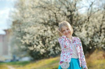 Beautiful happy little girl  enjoying smell in a flowering sprin