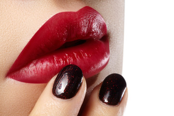 Close-up of woman's lips with fashion red make-up and manicure. Beautiful female full lips with perfect makeup. Classic visage. Part of female face. Macro shot of beautiful make up on full lips.