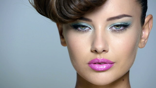 Closeup face of a beautiful  girl with blue eye makeup and pink lips. Full hd video clip.