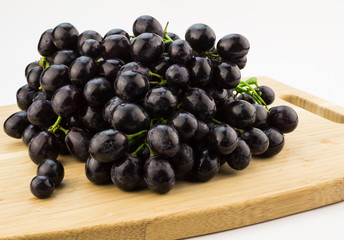Big bunch of black grapes on wood cutting board
